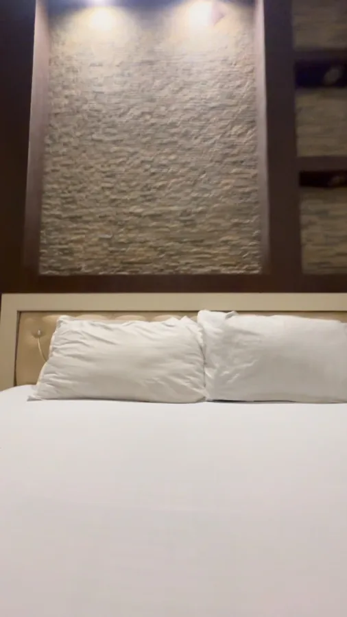 Hotel Max white bedding below a textured wall and reading lights
