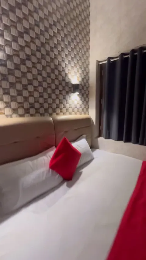 Close view of the bed, red cushion and padded headboard at Hotel Max